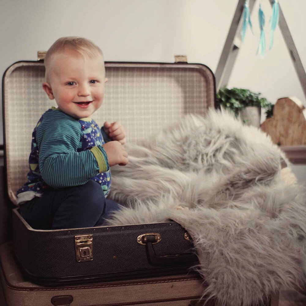 Lachender Junge sitzt in einem alten Koffer